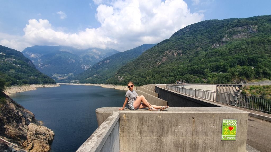 dziewczyna siedząca na murze tamy contra, Bungee w Szwajcarii, Verzasca Dam